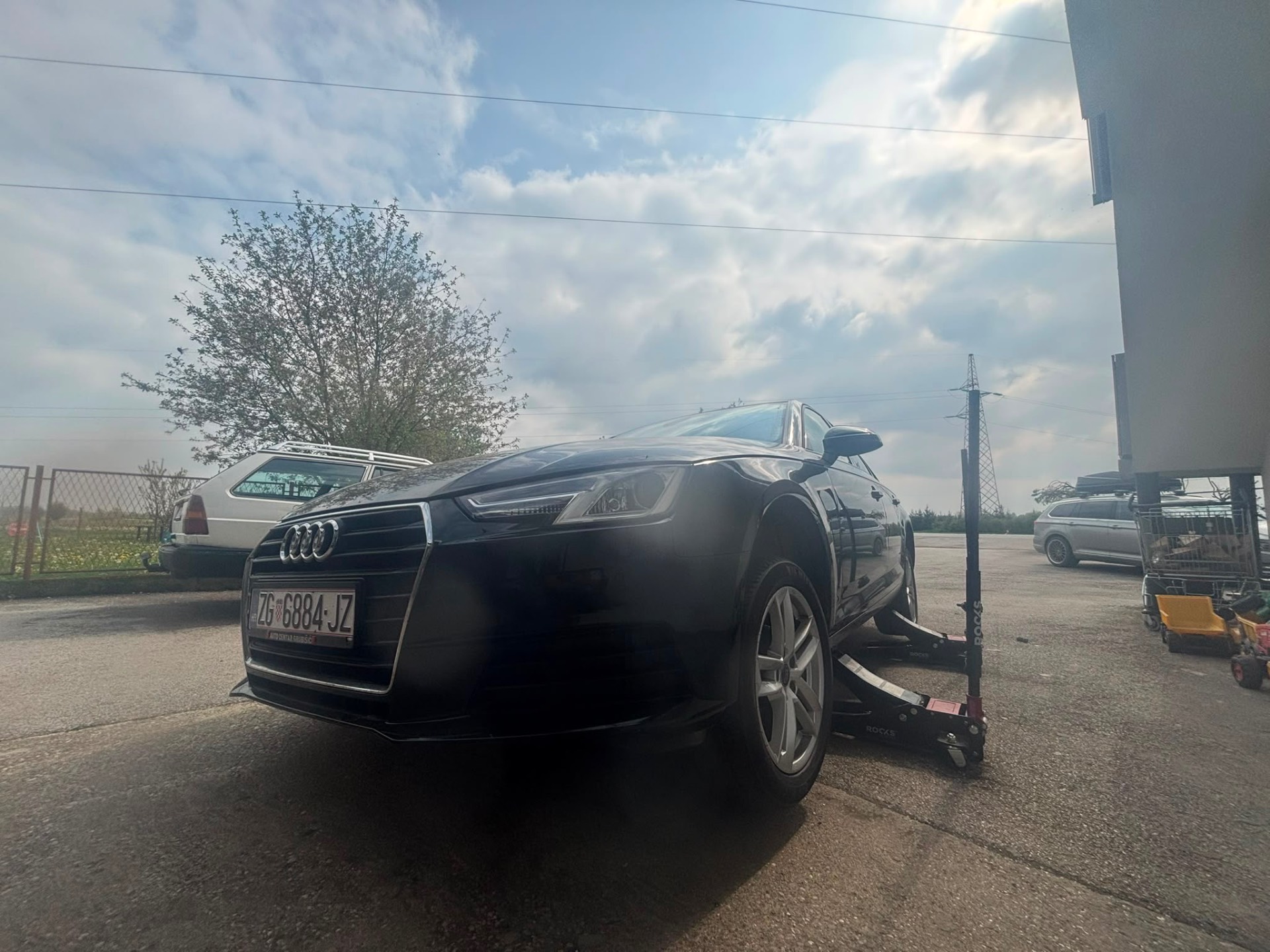 Black Audi A4 on service jack — tire change in progress